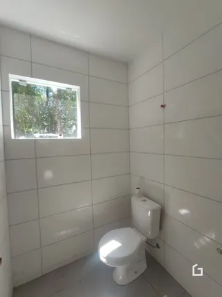 A foto mostra uma parede branca com uma janela e um vaso sanitário.