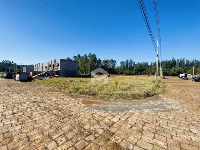 A foto mostra uma área externa de construção com terreno gramado e um edifício em fase de obra.