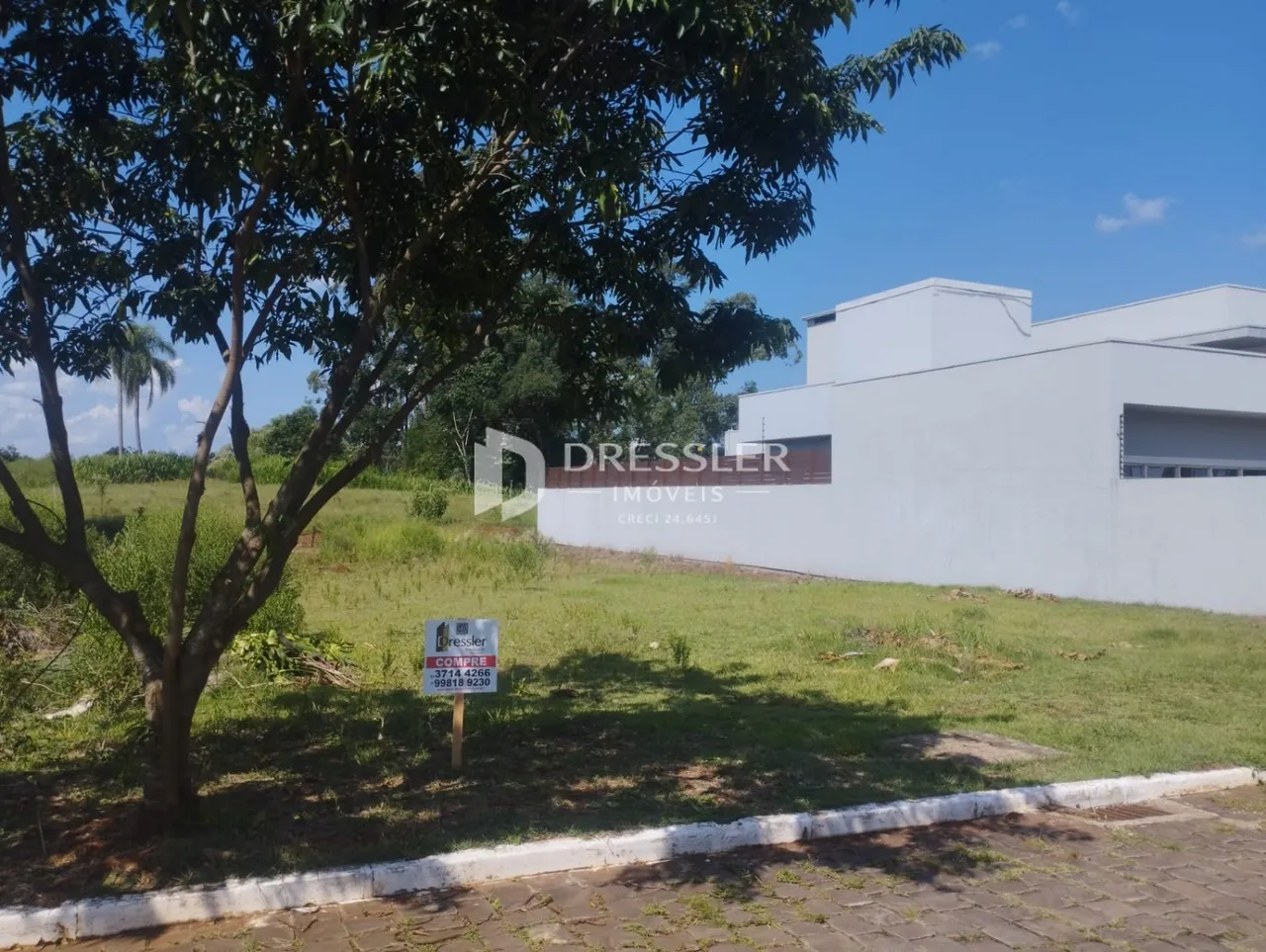 Vista externa de uma propriedade com gramado e cerca.