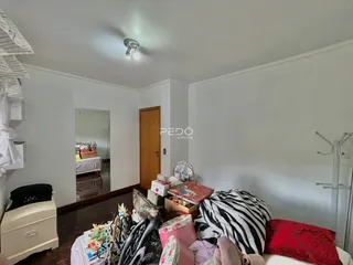 Quarto com piso de madeira escura e porta de madeira na sala.