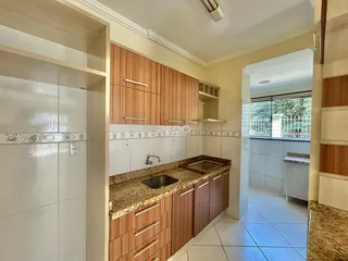 Vista da cozinha com armários de madeira e bancada de granito.