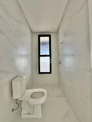 Banheiro com revestimento de mármore branco e janela.
