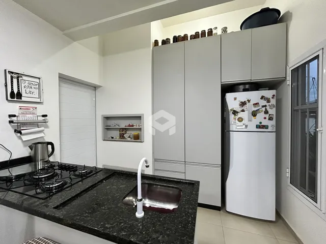 Foto de uma cozinha com bancada escura e armários brancos.