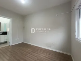 Ambiente interno de uma sala com piso de madeira clara.