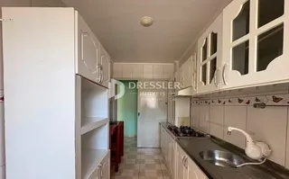 Uma cozinha com armários brancos e piso de cerâmica.