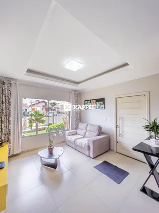 Sala de estar clara com sofá e grandes janelas que dão vista para o exterior.