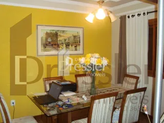 Sala de jantar com mesa de madeira e pintura na parede amarela.