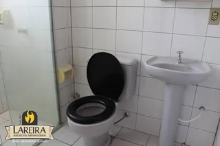 Foto de um banheiro com azulejos brancos e louças sanitárias.