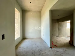 Vista interna de um ambiente com paredes brancas e piso de concreto aparente.