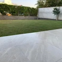 Vista externa mostrando um gramado e piso de concreto em uma propriedade.