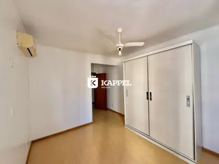 Foto de um corredor interno com paredes brancas e piso de madeira clara.
