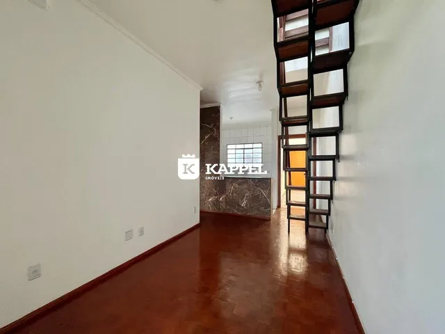 Hall de entrada com piso de madeira polida e escadaria escura.