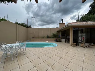 Foto da área externa com piscina e deck de azulejos em uma residência.