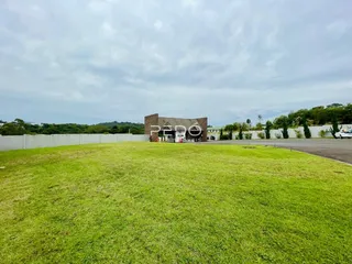 Vista externa de uma propriedade com gramado verde e muro de vedação.