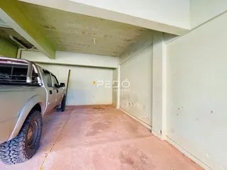 Foto de um espaço interno com piso de concreto e estrutura de teto exposta.