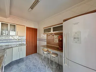 Vista interna de uma cozinha com armários e eletrodomésticos.