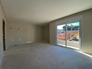 Ambiente interno vazio com piso de concreto e porta de vidro que dá para um campo.