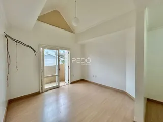 Interior de uma sala com piso de madeira clara e porta de vidro.