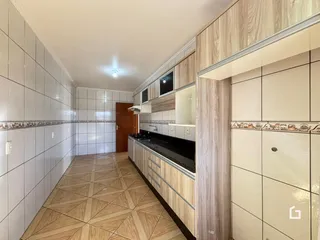 Vista de um corredor com revestimento de cerâmica e armários de madeira na cozinha.