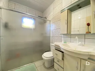 Foto de um banheiro com box de vidro e pia branca.