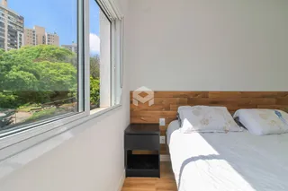 Quarto com grande janela e vista para a vegetação externa.