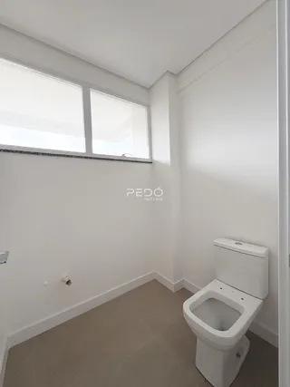 Foto de um banheiro interno com piso claro e vaso sanitário branco.