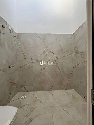 Interior de um banheiro com revestimento de mármore nas paredes e piso.
