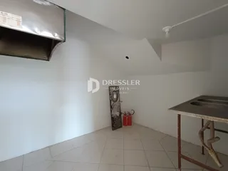 Vista interna de um ambiente com paredes brancas e piso de cerâmica.