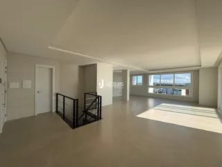 Sala de estar ampla com piso claro e grande janela.