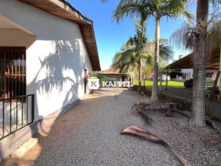 Exterior da casa com paredes brancas e telhado de madeira em Lajeado.