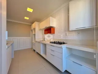Cozinha moderna com armários brancos e piso claro.