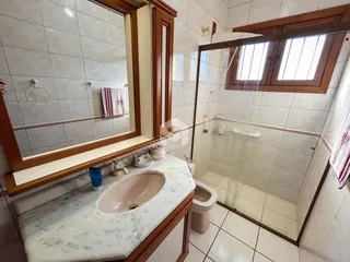 Banheiro com box de vidro e pia de mármore na Lajeado.