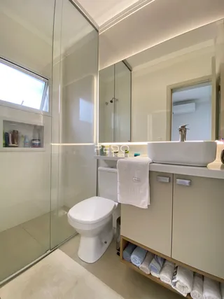 Interior de um banheiro com box de vidro.