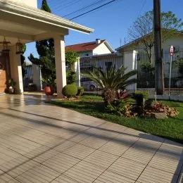 Vista da fachada de uma residência com calçada e gramado verde.