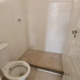 Foto de um banheiro com piso de cerâmica e vaso sanitário branco.
