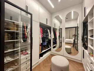 Quarto com armários brancos e piso de madeira clara.