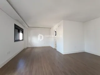 Ambiente interno de uma sala ampla com piso de madeira clara.