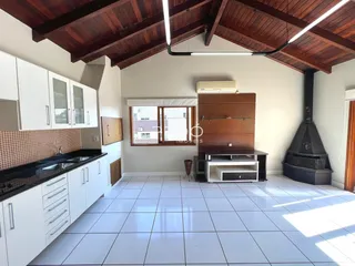 Imagem de uma área de estar e cozinha com piso de cerâmica clara.