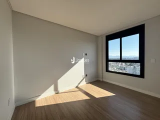 Sala de estar com piso de madeira e grande janela de vista para a cidade.