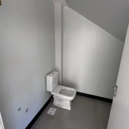 Foto de um banheiro com vaso sanitário branco e paredes brancas.