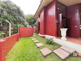 Fachada de casa em tijolo vermelho com jardim e muro de alvenaria.