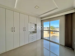 Interior de uma sala com armários brancos e porta de vidro que dá para o exterior.