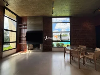 Sala de estar com paredes de tijolo e grandes janelas.
