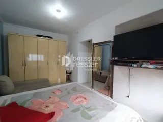 Quarto com cama e parede clara em imóvel no Brasil.