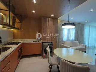 Ambiente de sala de estar e cozinha com piso claro e móveis modernos.
