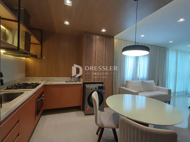 Ambiente de sala de estar e cozinha com piso claro e móveis modernos.