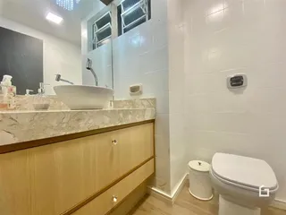 Banheiro com bancada de mármore e vaso sanitário.
