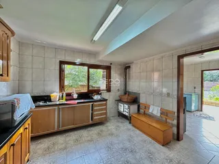 Interior da cozinha com piso de cerâmica e janela de madeira.
