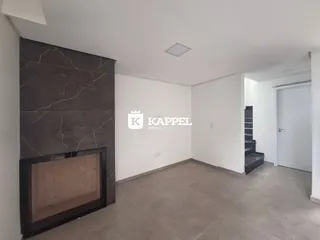 Sala de estar com parede de pedra escura e piso de concreto claro.