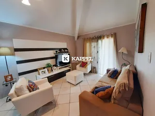 Sala de estar com sofá e televisão em ambiente claro.
